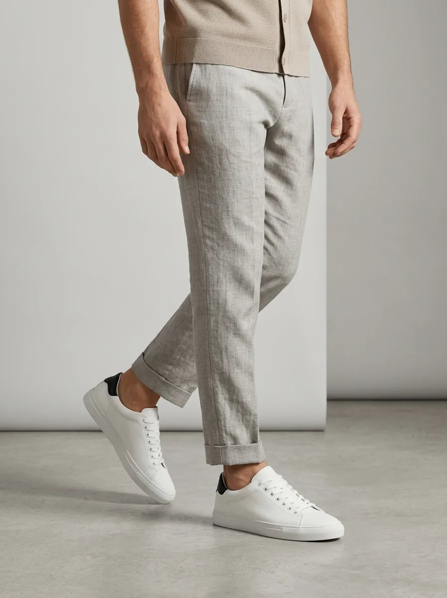 Man walking in light grey linen-blend trousers with white trainers featuring a black heel tab