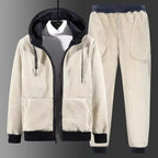 Cream sherpa fleece tracksuit with navy trims, hood up over a white jumper, hung against a grey backdrop