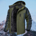 Men's khaki green winter jacket with hood open, showing black faux fur lining and zip chest pocket, mountain backdrop
