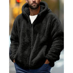 Man wearing a black fluffy fleece zip-up hoodie with the hood up, styled with dark jeans and a white t-shirt underneath