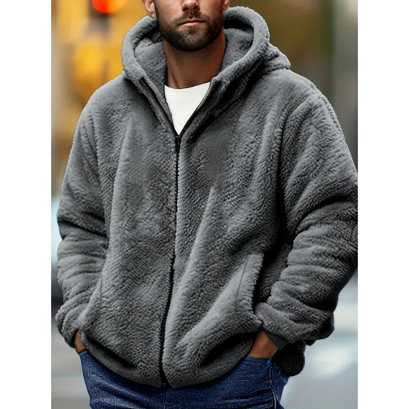 Man wearing a grey fluffy fleece zip-up hoodie with hands in the pockets, paired with jeans for a casual look