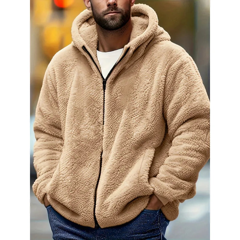 Man wearing a beige fluffy fleece zip-up hoodie with the hood up, shown in an outdoor urban setting