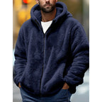 Man wearing a navy blue fluffy fleece zip-up hoodie with hood up and hands tucked into the front pockets