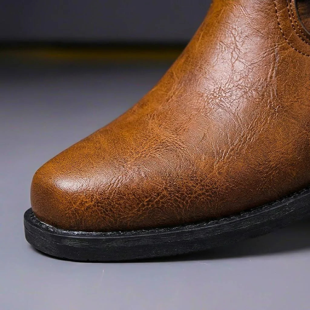 Close-up of the round toe cap on a cognac brown leather boot showing natural grain texture and stitched seam