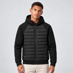 Front view of man wearing a black hooded puffer jacket with quilted front panels and fleece sleeves