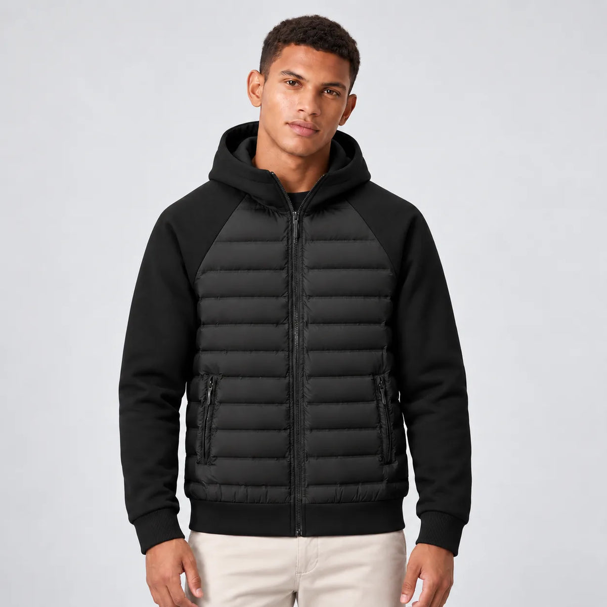 Front view of man wearing a black hooded puffer jacket with quilted front panels and fleece sleeves