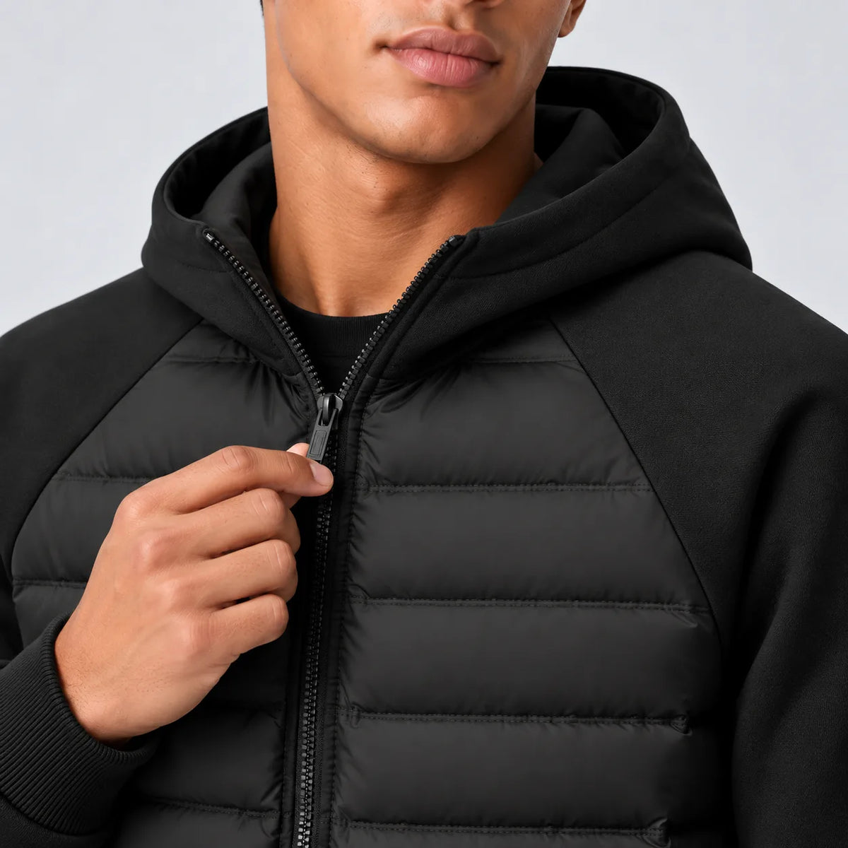 Close-up of the front zip and hood lining detail on the black quilted jacket