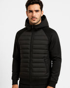 Close-up front view of a man wearing the black hooded puffer jacket, zipped up with hood raised