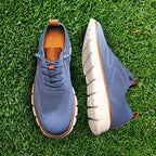 Blue knit lace-up trainer with tan leather heel pull shown on a grass background