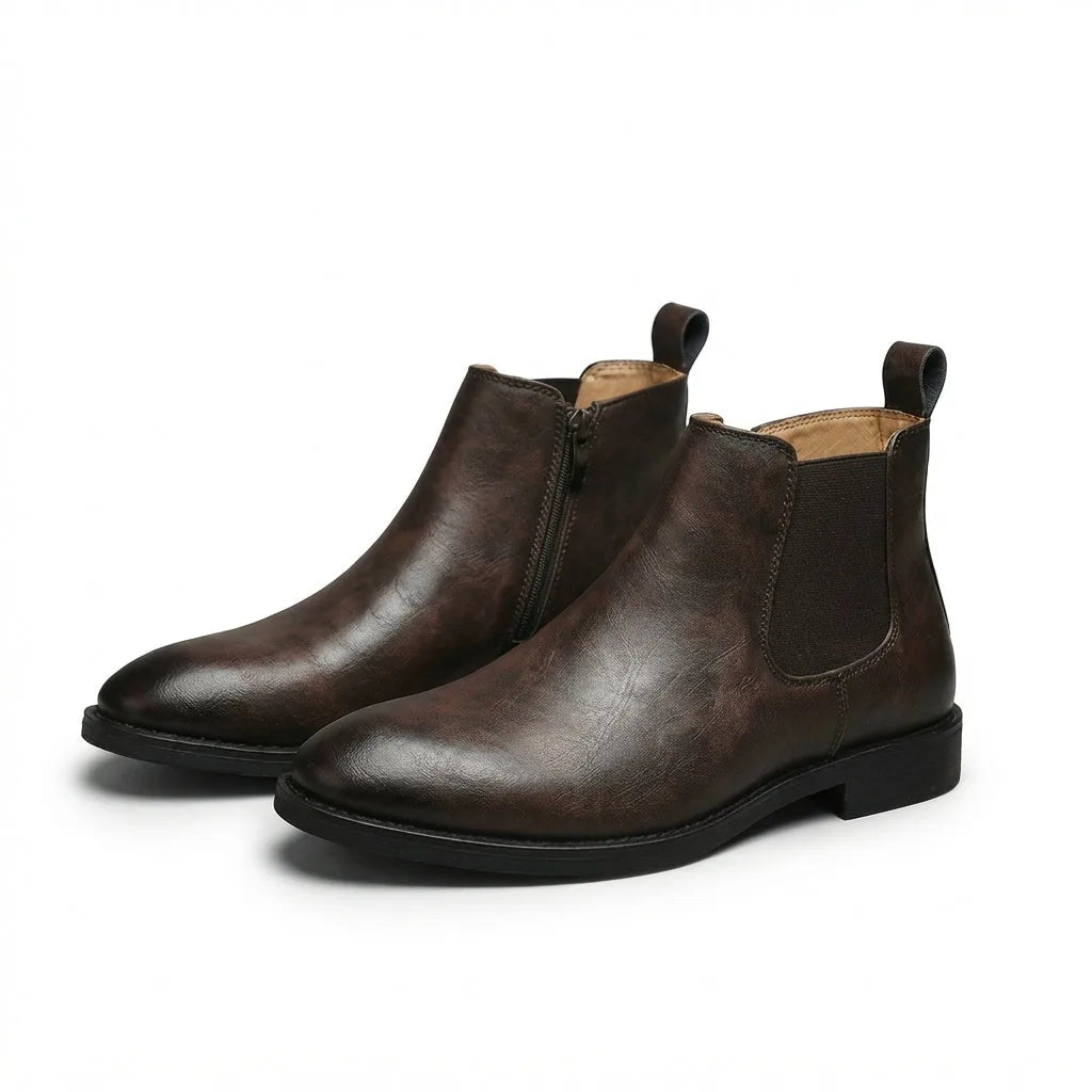 Three-quarter view of a pair of dark brown leather Chelsea boots with side zip fastening and elastic gussets