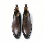 Top-down view of a pair of dark brown leather Chelsea boots showing pull tabs and almond-shaped toes