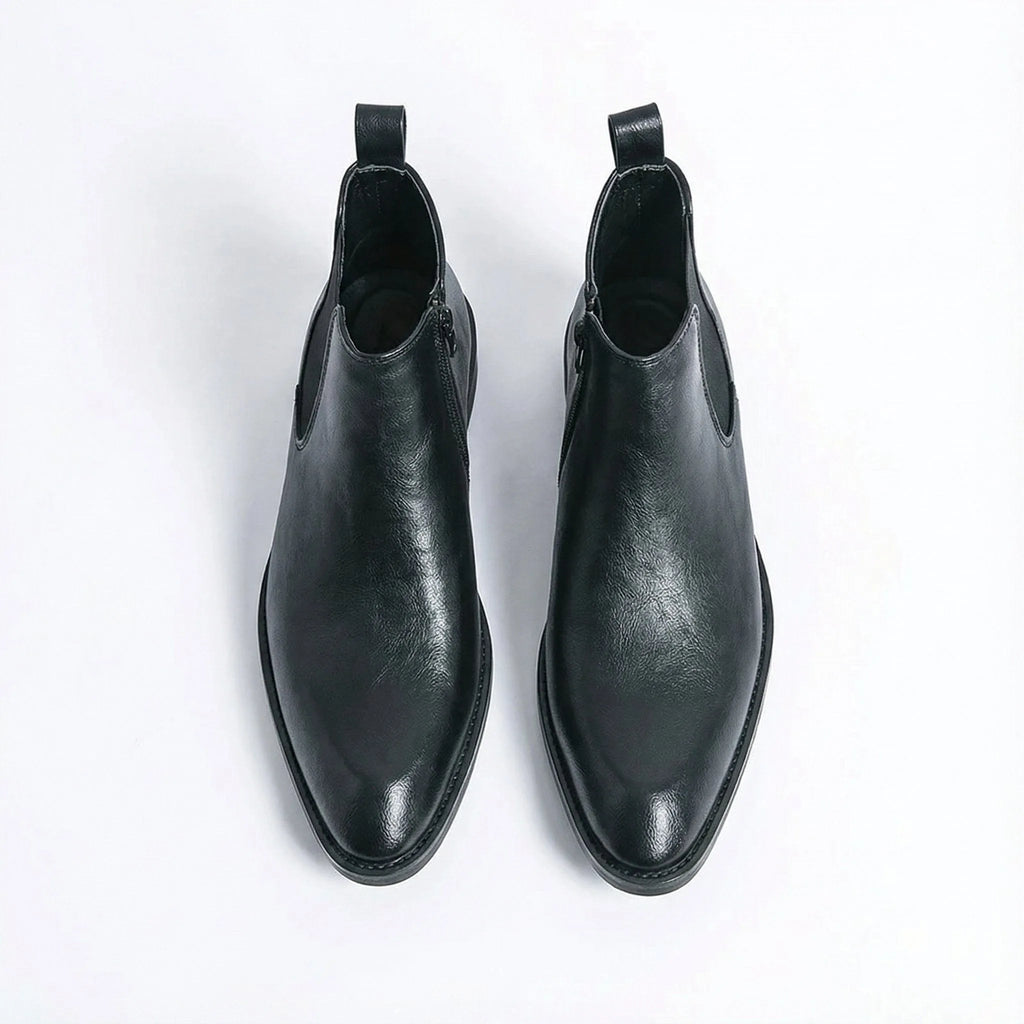 Top-down view of a pair of black leather Chelsea boots with side zip and tan leather lining