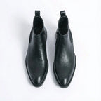 Top-down view of a pair of black leather Chelsea boots with side zip and tan leather lining