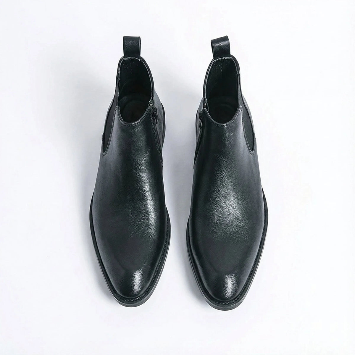 Top-down view of a pair of black leather Chelsea boots with side zip and tan leather lining