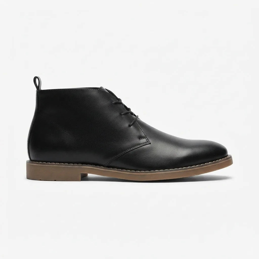 Side profile of a black leather desert boot with gum sole and stitched welt detail