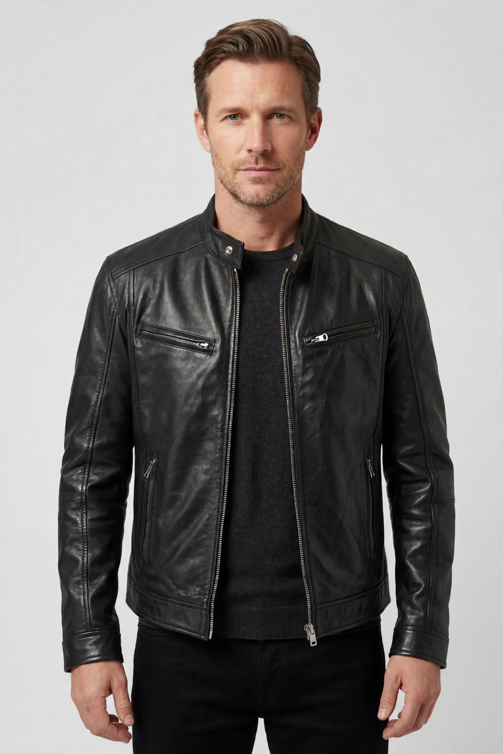 Front view of a man wearing a black leather biker jacket with silver zip fastening over a dark jumper