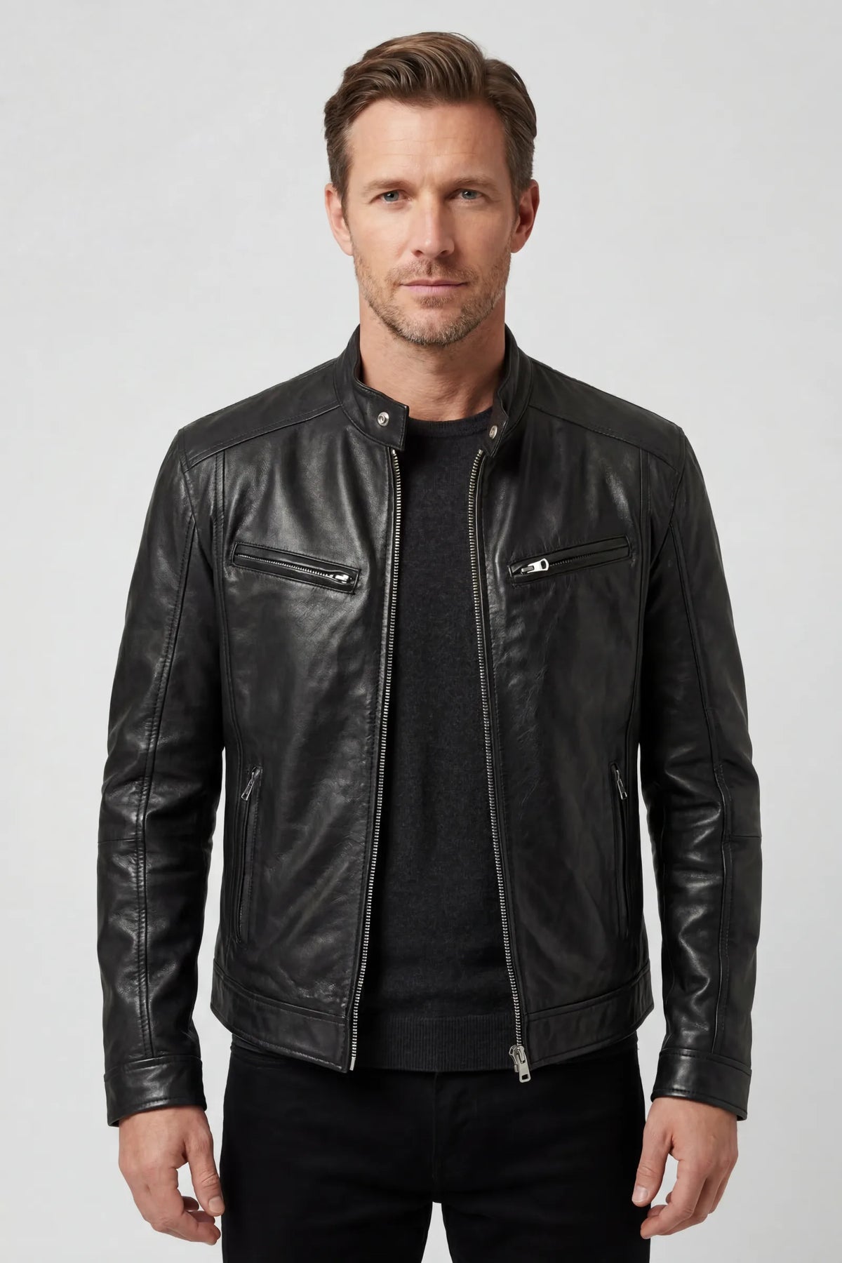 Front view of a man wearing a black leather biker jacket with silver zip fastening over a dark jumper