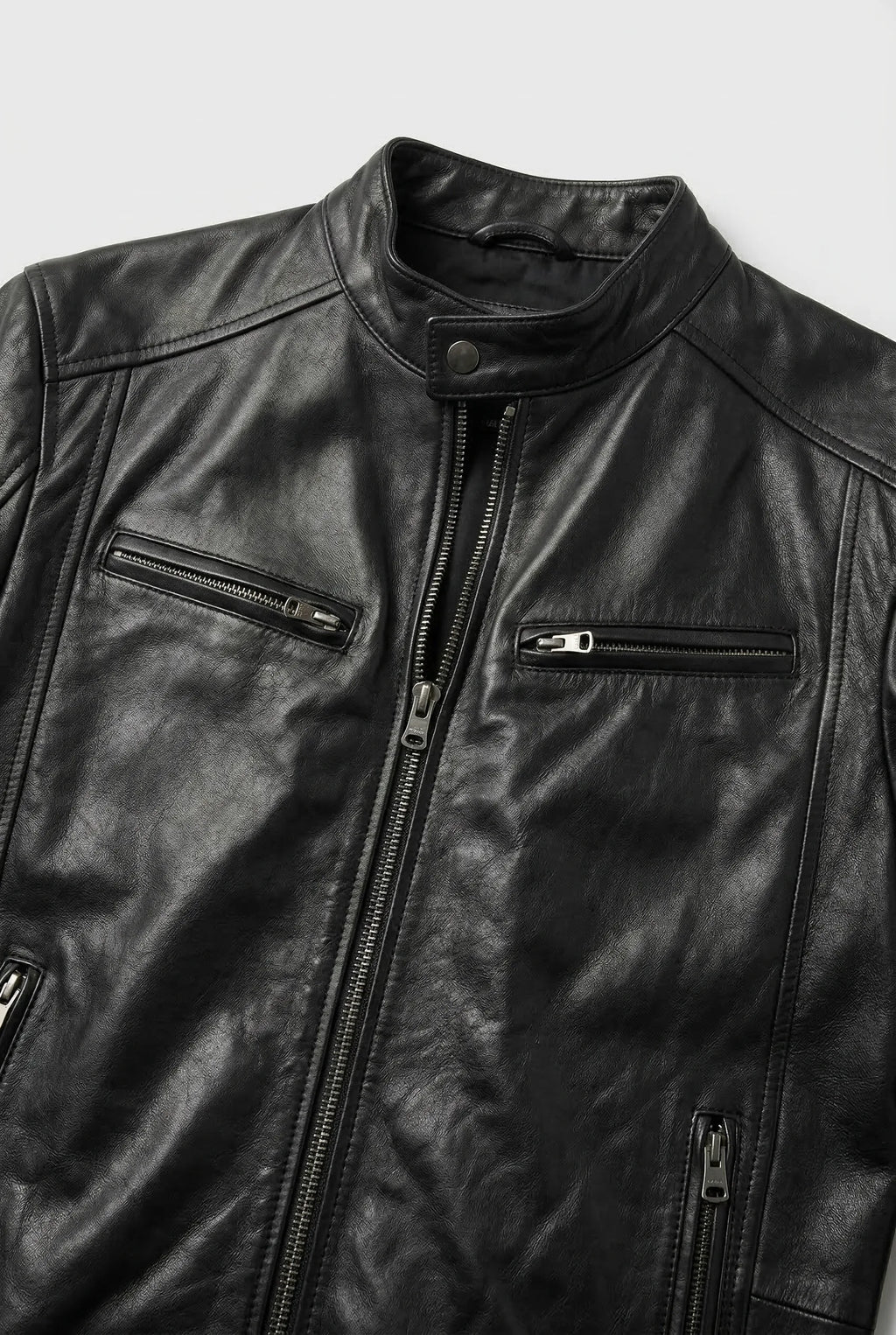 Close-up of the black leather jacket collar, snap button neck and two zip chest pockets