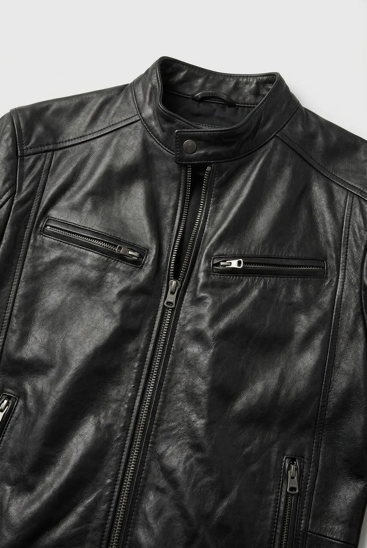 Close-up of the black leather jacket collar, snap button neck and two zip chest pockets