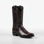 Three-quarter view of a brown leather cowboy boot showing the pointed toe, pull tab and detailed western stitching