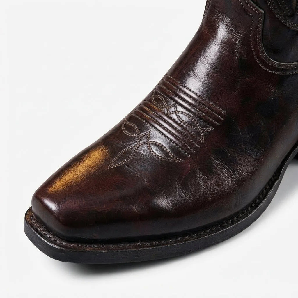 Close-up of the brown leather boot toe highlighting the polished finish, decorative stitching and ridged sole edge