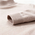 Detail shot of the ribbed cuff on a beige knit sleeve, folded to show stitch construction