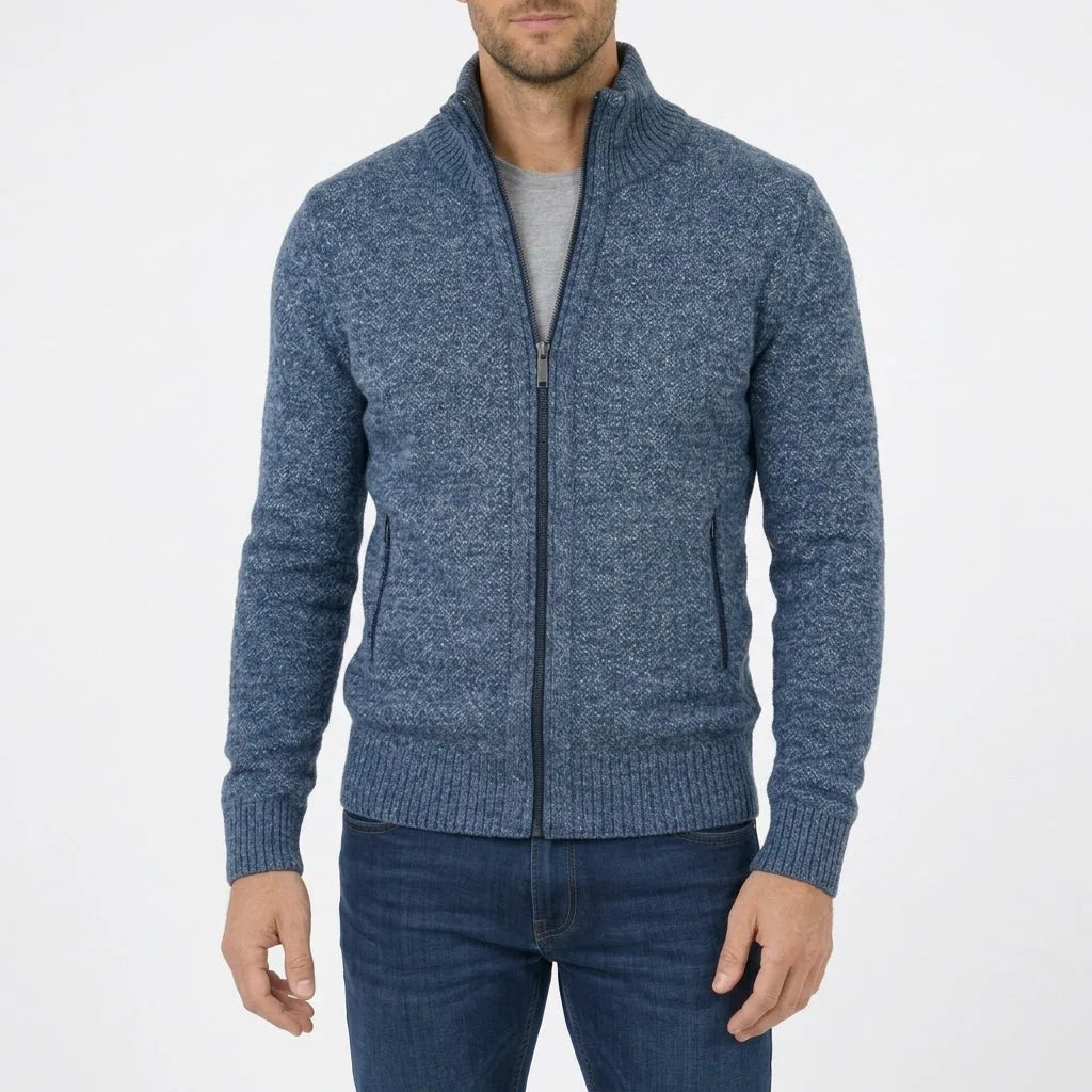 Man wearing a denim blue marl zip-through knit jumper with ribbed stand collar and zip pockets, front view