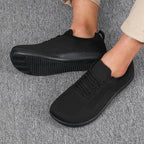 Angled view of men's black mesh trainers with lace detail and matching black ridged sole