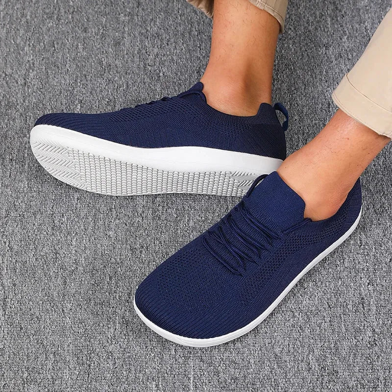Side profile of navy knit trainers on feet with white sole and lace-up front panel