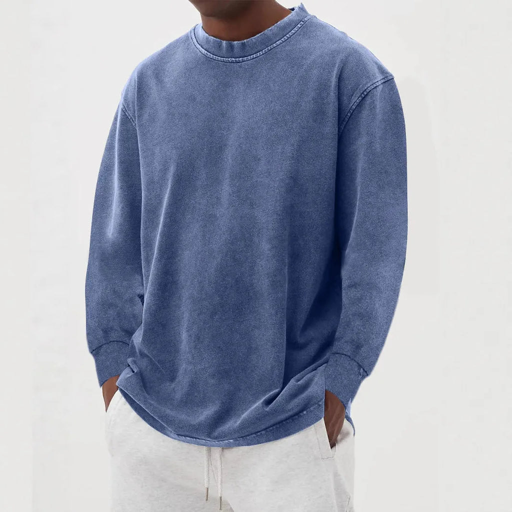 Front view of a man wearing a dark blue oversized long-sleeve knit jumper with a washed, faded finish over grey joggers