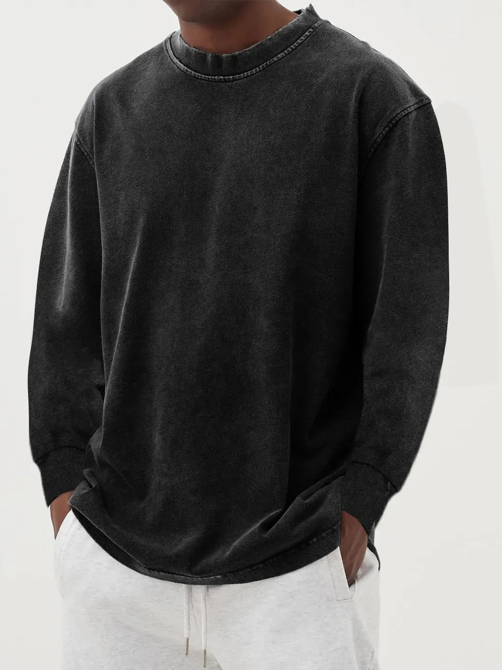 Close-up front view of a black washed knit jumper showing the raw-edge crew neckline and relaxed fit