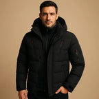 Black padded puffer jacket with hood up, black zip pockets and ribbed cuffs, close front view.