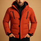 Close-up of an orange quilted puffer jacket showing hood lining, chest zip pockets and sleeve pocket detail.