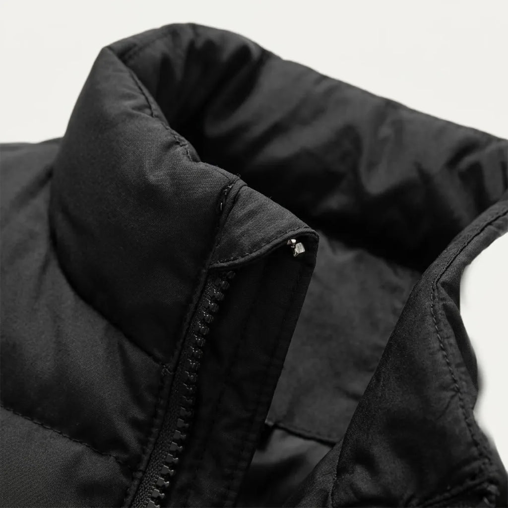 Close-up of the zip pull and collar on a navy blue quilted gilet