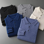 Five folded polo jumpers in black, grey, white, navy and blue arranged together to show the full colour range