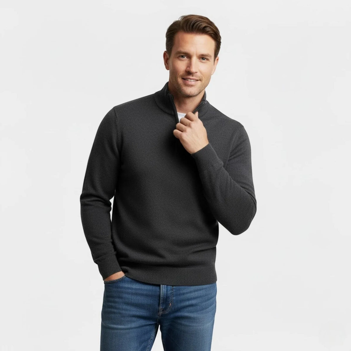 Man wearing a charcoal grey quarter-zip jumper, holding the collar with one hand, paired with blue jeans