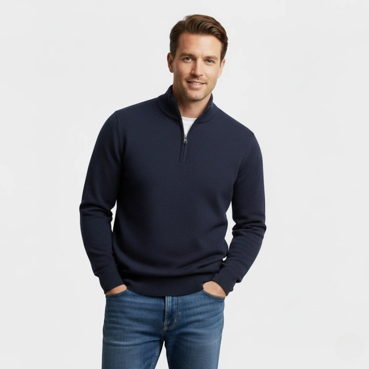 Man wearing a navy textured quarter-zip jumper with a white tee underneath and jeans, hands in pockets