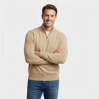 Man wearing a beige quarter-zip jumper with arms folded, paired with blue jeans