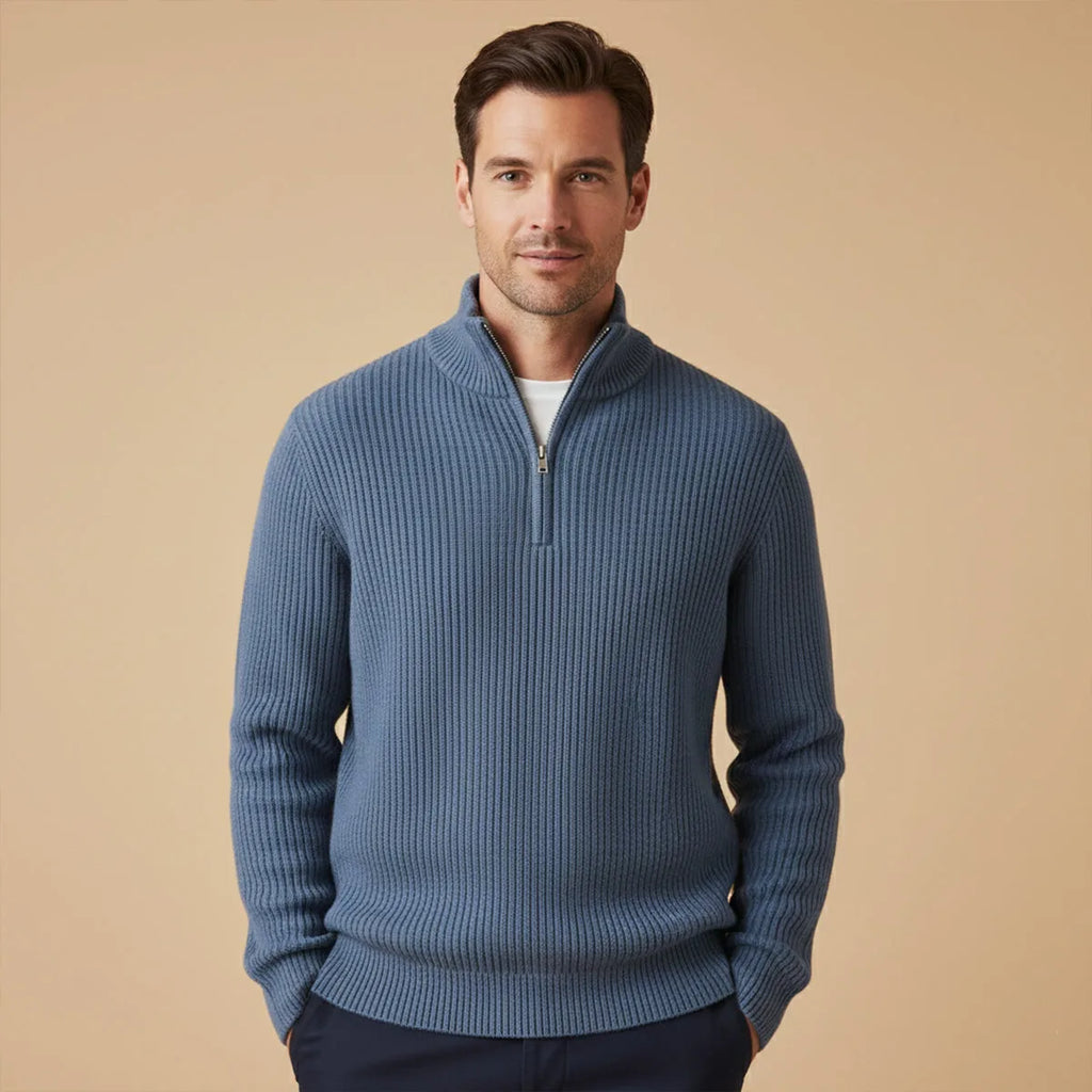 Man wearing navy blue ribbed half-zip jumper with white t-shirt underneath and navy trousers