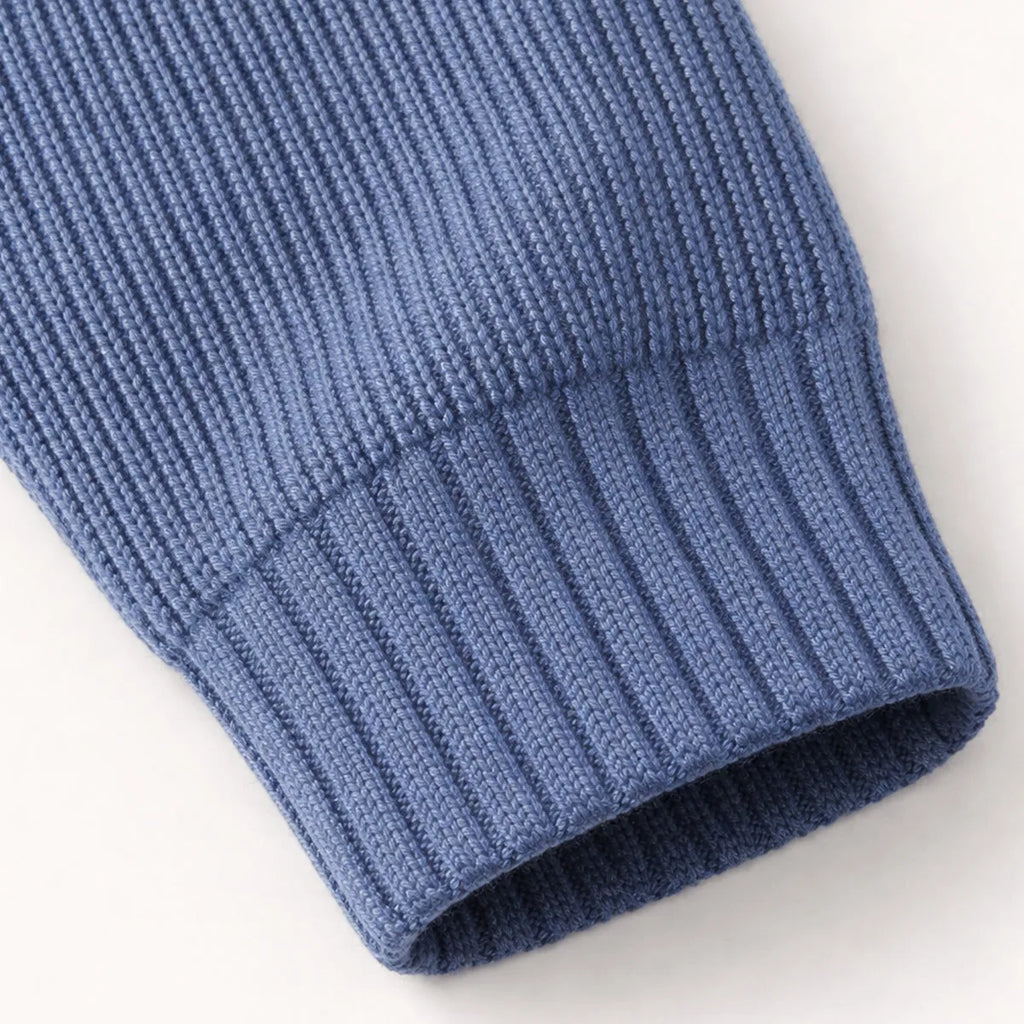 Close-up of the ribbed cuff on the sleeve of the navy blue knit jumper