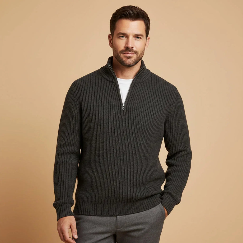 Man wearing black ribbed half-zip jumper with white t-shirt and grey trousers