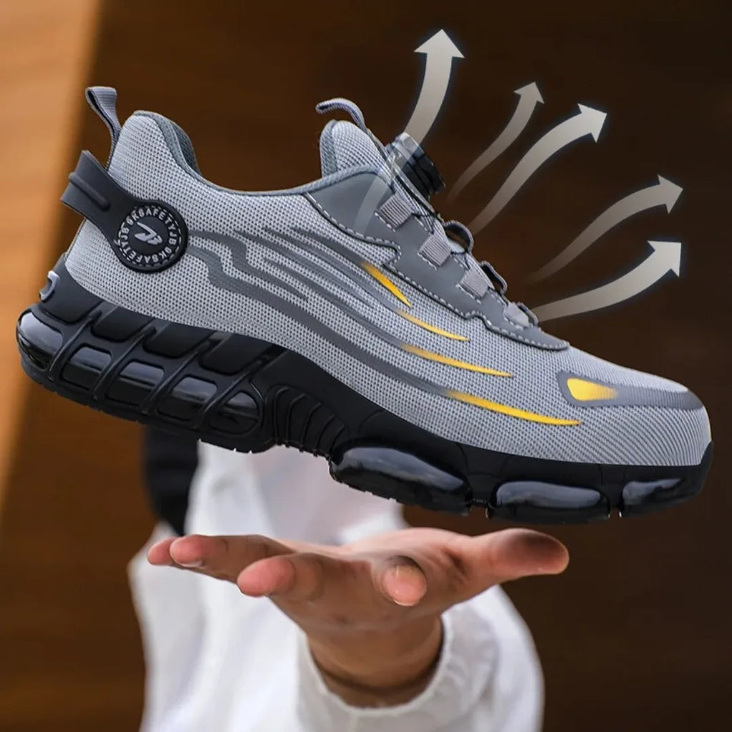 Grey and black mesh safety trainer floating above an open hand, with airflow arrows highlighting the breathable upper