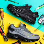 Pair of safety trainers, one black and one grey, laid diagonally on a teal and yellow background surrounded by work tools