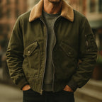 Front view of olive green cotton bomber jacket with shearling collar worn open over a grey jumper