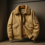 Tan bomber jacket on a wooden hanger, fully zipped open showing fleece lining and chest flap pockets