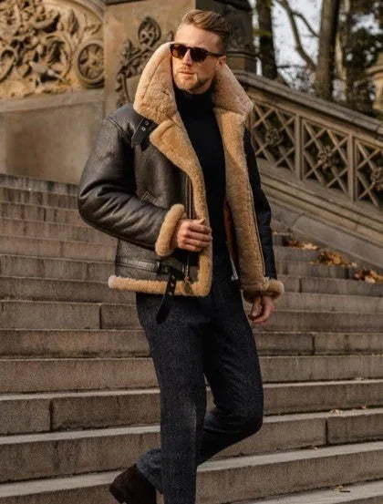 Man walking down stone steps in a brown shearling leather jacket layered over a black polo neck with dark trousers