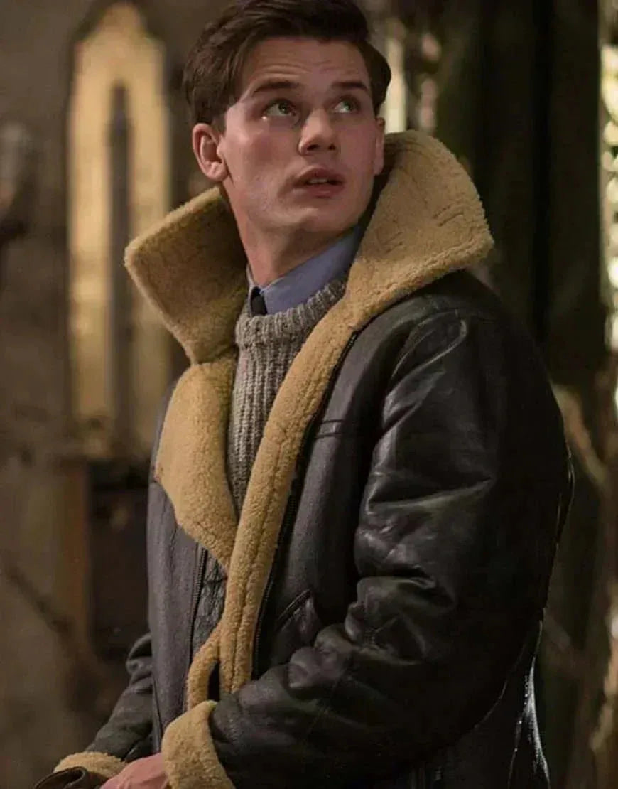 Young man looking upward wearing a dark leather aviator jacket with tan shearling collar over a grey knit jumper