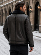 Back view of the black leather aviator jacket showing the shearling-lined collar, side seams and adjustable hem strap.