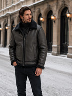 Front three-quarter view of the black aviator jacket with hands in pockets, showing the shearling cuffs and collar.
