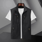 Black sleeveless zip-up gilet with stand collar and multiple zip pockets, shown open over a white t-shirt on a hanger